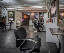 Moderner Friseursalon mit schwarzen Stühlen und großen Spiegeln in einem eleganten Ambiente.