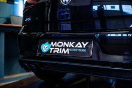 Sort bil med "Monkay Trim" nummerplade i garage.