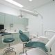 Studio dentistico moderno con poltrona verde, lampada e strumenti odontoiatrici.