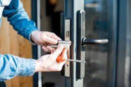 Person repairing a door lock using a screwdriver.