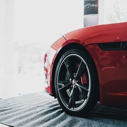 Close-up of a red sports car's front wheel on display in a bright showroom.