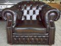 Dunkelbrauner Ledersessel im Chesterfield-Stil mit Knopfheftung, steht auf einem Boden.