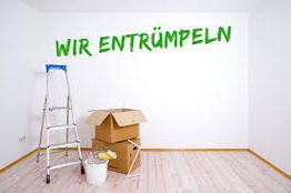 Leiter, Kartons und Eimer in leerem Raum, Schrift an der Wand: "WIR ENTRÜMPELN".