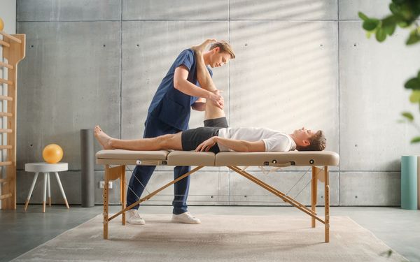 Physiotherapeut behandelt Knie von seinem Patienten