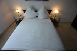 Ein ordentlich gemachtes Bett mit zwei Nachttischlampen auf beiden Seiten.