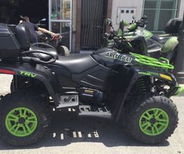 ATV negro con detalles verdes estacionado en la calle, marca y modelo visibles en el chasis.