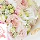 Bruidsboeket met roze en witte bloemen en twee gouden ringen op witte achtergrond.
