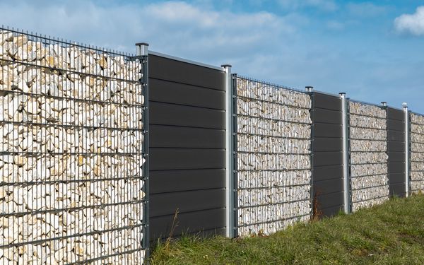 Ein Zaun aus sich abwechselnden Gabionen und WPC-Sichtschutzelementen.