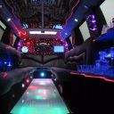 Interior of a party bus with colorful lights, bar setup, and seating.