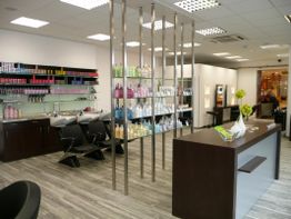 Moderner Friseursalon mit Regalen voller Produkte und zwei Waschstationen.
