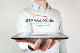 Mann hält Tablet mit strahlendem Logo "STP WebMedia Full-Service Agentur" in der Hand.