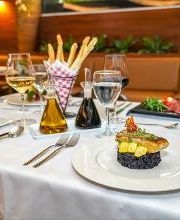 Mesa elegante con platos gourmet, copas de vino y decoraciones en un restaurante.