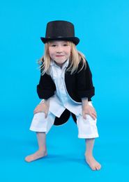 Kind mit Zylinder, schwarzem Jackett und weißem Hemd, posiert auf blauem Hintergrund.