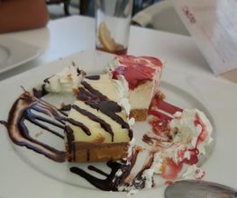 Trozos de tarta con crema y chocolate en un plato, con vaso vacío y cuchara al lado.