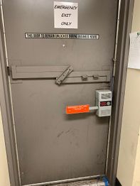 Emergency exit door with signs indicating it should remain unlocked during business hours.