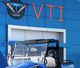 Blue building labeled "VTI" with a parked blue vehicle and a U.S. flag.