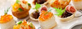 Verschiedene bunte Canapés mit Kaviar, Schinken und Gemüse auf einem Tablett angerichtet.