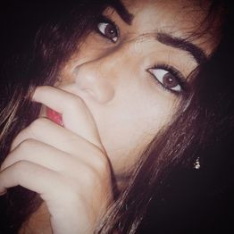 Jovem de olhos castanhos e cabelo longo, com a mão no rosto, em close no olhar intenso.