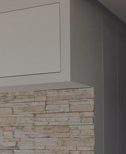 Eckiger Raum mit Steinmauer und grauen Wänden.