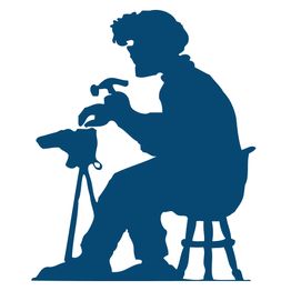 Silhouet van een persoon die op een kruk zit en iets repareert met een hamer.