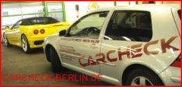 Zwei Autos in einer Werkstatt, ein gelber Sportwagen und ein silberner Wagen mit "Carcheck"-Aufschrift.