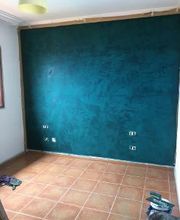 Habitación con pared azul turquesa y suelo de baldosas marrones. herramientas en el suelo.