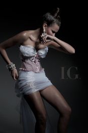 Frau in elegantem Kleid mit hochgestecktem Haar und auffälligem Schmuck in gedämpftem Licht.