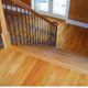 Wooden staircase with black iron balusters leading down to a bright room with hardwood floors.