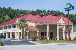 Days Inn hotel with red roof, surrounded by trees and parking lot under a clear blue sky.