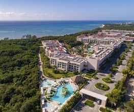 Complejo turístico frente al mar con piscinas rodeado de vegetación.