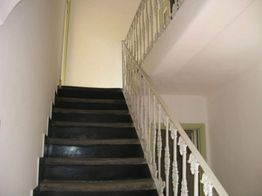 Scala interna con gradini neri e ringhiera bianca decorata. Pareti chiare intorno.