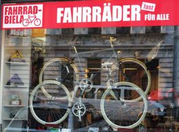 Schaufenster mit Fahrrädern und Werbeschild: "FAHRRÄDER (fast) FÜR ALLE" in Rot und Weiß.
