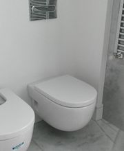 Baño moderno con bidé y váter de diseño minimalista en una pared blanca.