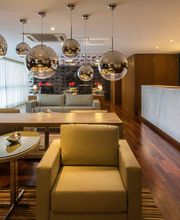 Sala moderna com poltronas, balcão e luminárias esféricas. Decoração elegante e sofisticada.