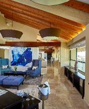 Sala de estar moderna con techo de vigas de madera, arte azul y sofás amplios.