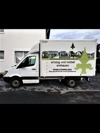 Lieferwagen mit Werbung für Umzugs- und Möbeleinbau-Service, geparkt auf einer Straße.