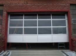 A partially open white garage door on a red brick building.