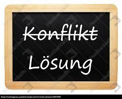 Tafel mit der Aufschrift "Konflikt Lösung" in weißer Schrift auf schwarzem Hintergrund.