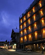Beleuchtetes Hotel in winterlicher Stadtstraße bei Abenddämmerung.
