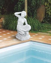 Steinstatue einer sitzenden Frau mit Muschel, neben einem Pool platziert.