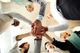 A group of people standing in a circle with their hands stacked together, viewed from below.