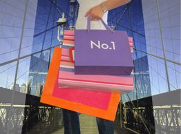 Person mit bunten Einkaufstaschen auf einer Brücke.