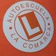 Logo de autoescuela "La Comarca" en fondo naranja con letra L en el centro.