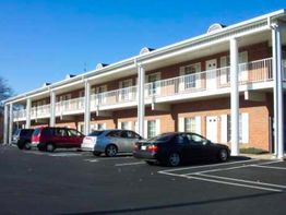 Two-story motel with parked cars and clear blue sky.