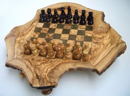 Schachbrett auf unregelmäßig geformtem Holzbrett mit Spielfiguren in zwei Farben.