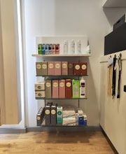 Plank met diverse schoonheidsproducten in een winkel, kleurrijke dozen en flessen op de vloer.