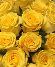 Ramo de rosas amarillas vibrantes frente a un fondo de madera gris.