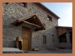 Fachada de piedra rústica con puerta de madera bajo un pequeño techo inclinado.