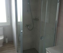 Ducha de vidrio en un baño moderno con luz natural entrando por la ventana.