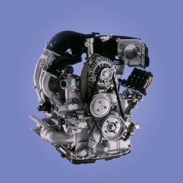 Moderner Motor mit Riemen und Metallteilen, vor blauem Hintergrund.